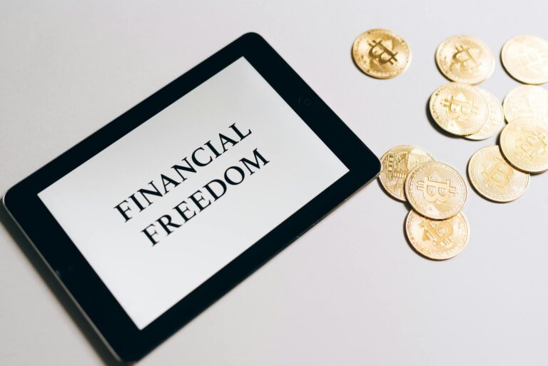 Tablet showing 'Financial Freedom' with gold bitcoins nearby, symbolizing cryptocurrency investment.